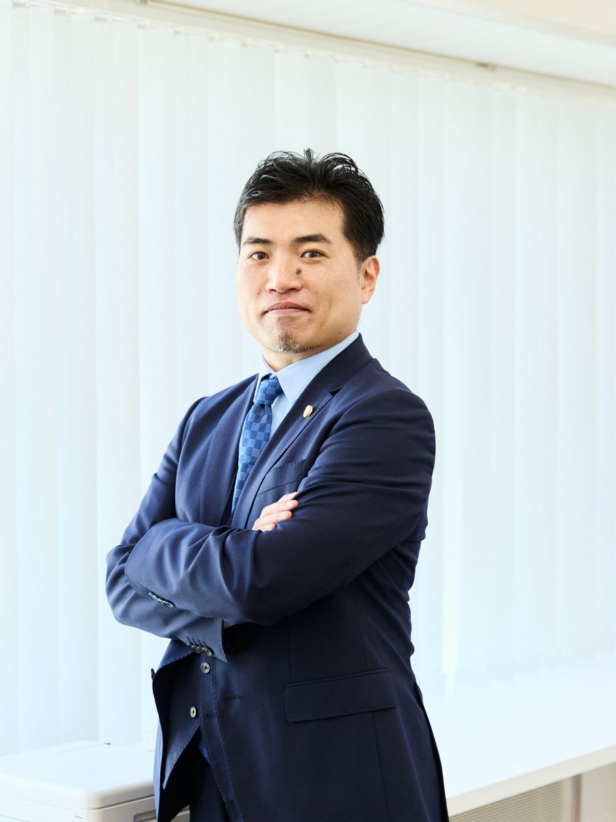 腕を組み、前を見すえる弁護士 福田 匡剛
